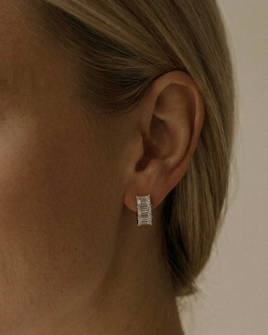 Lab grown emerald cut diamond huggie earrings with three diamonds per hoop in 14K white  gold on ear