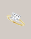 Two tone east west emerald cut solitaire engagement ring in 14K gold shown with a 1.75 ct centre diamond